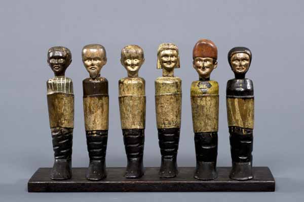 Nine pin shaped human figures carved out of wood